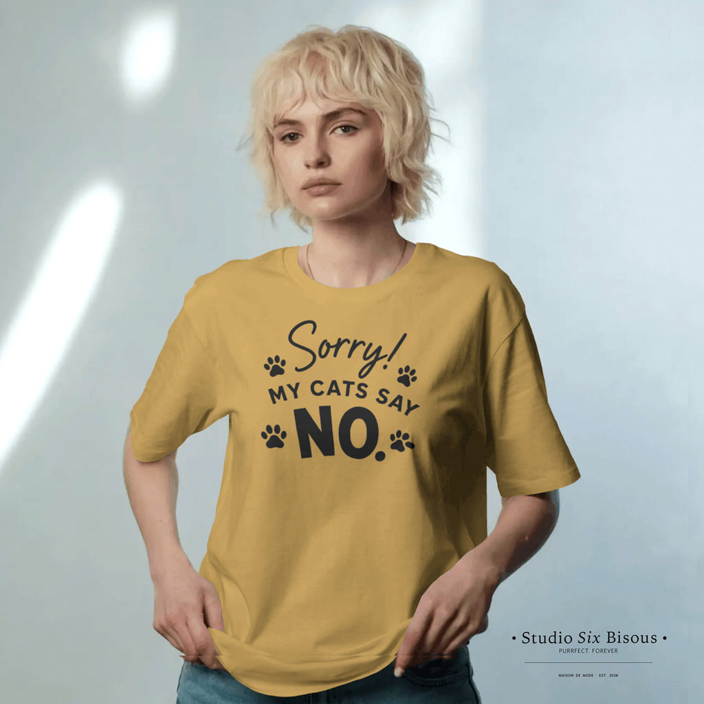 Model wearing a mustard yellow t-shirt with text 'Sorry! My cats say NO.' on a light gray background.