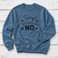 A slate blue crewneck sweatshirt with a black graphic print that reads 'Sorry! MY CATS SAY NO.' accompanied by small paw prints, laid flat on a white wood plank background.