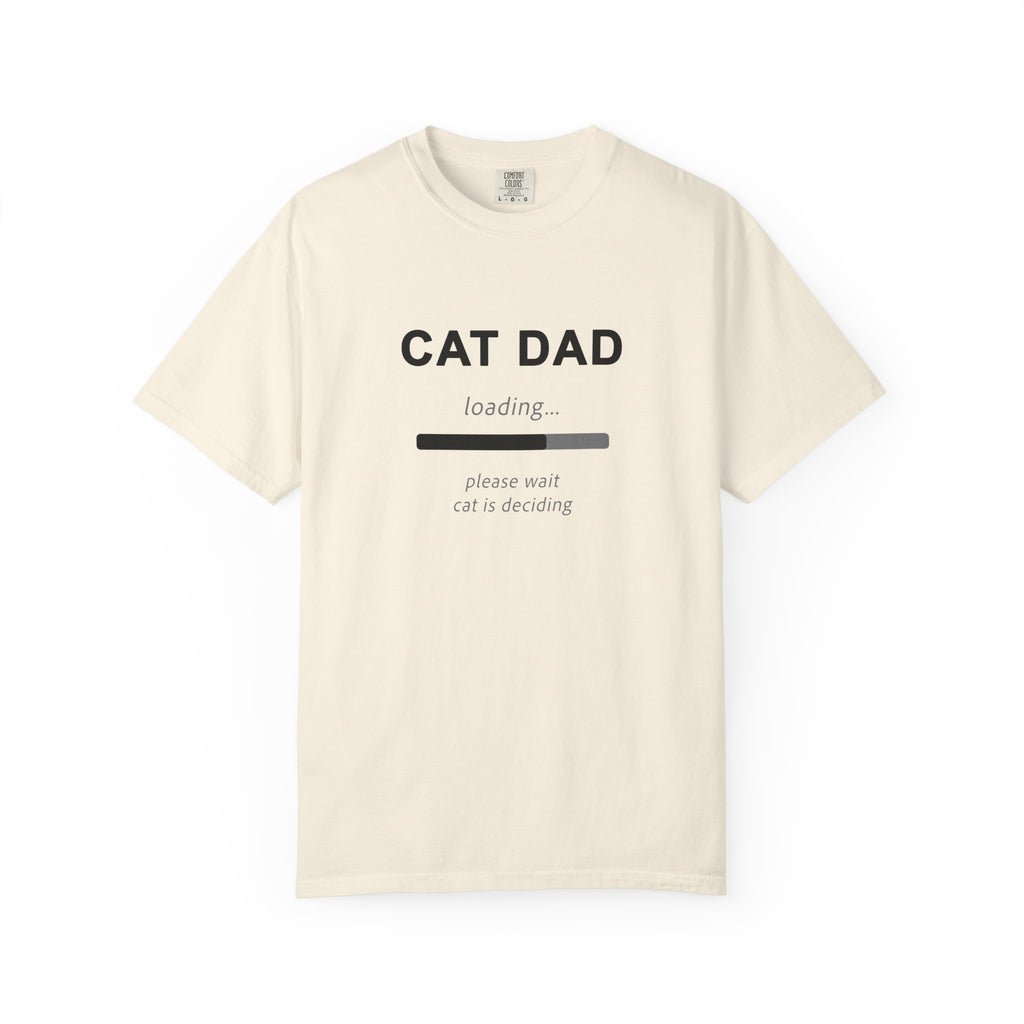 An off-white short-sleeve t-shirt with a black graphic print that reads 'CAT DAD' above a loading bar and the text 'please wait cat is deciding'.