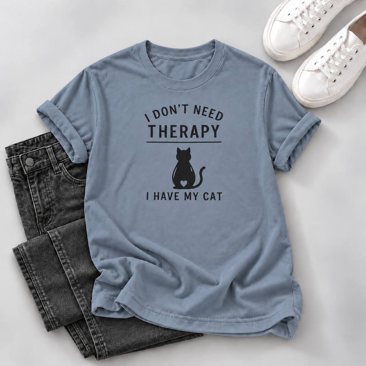Blue-gray T-shirt with black “I Don’t Need Therapy I Have My Cat” lettering and a seated cat silhouette with a heart cutout, on a white background.