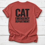 A rust-red t-shirt with 'CAT EMERGENCY DEPARTMENT' printed in bold black letters on the back, laid flat on a white wood plank background.