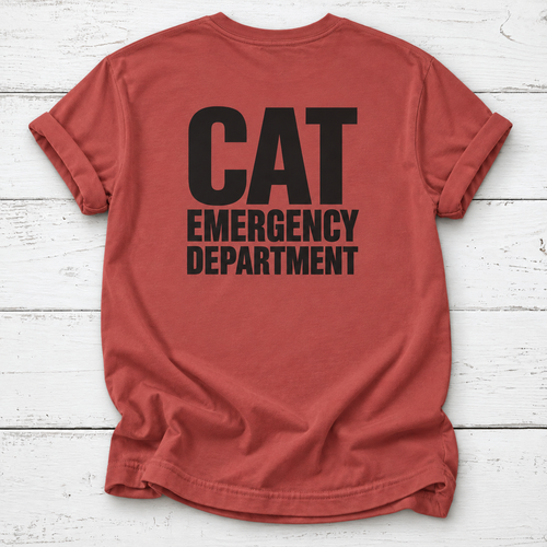 A rust-red t-shirt with 'CAT EMERGENCY DEPARTMENT' printed in bold black letters on the back, laid flat on a white wood plank background.