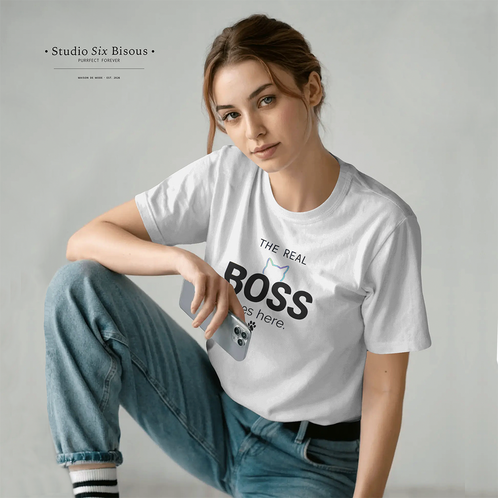 Person wearing a white t-shirt with 'The Real Boss is here' text and graphic, sitting on the floor against a plain background.