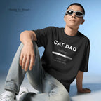 A man wearing a black graphic t-shirt with 'CAT DAD loading.