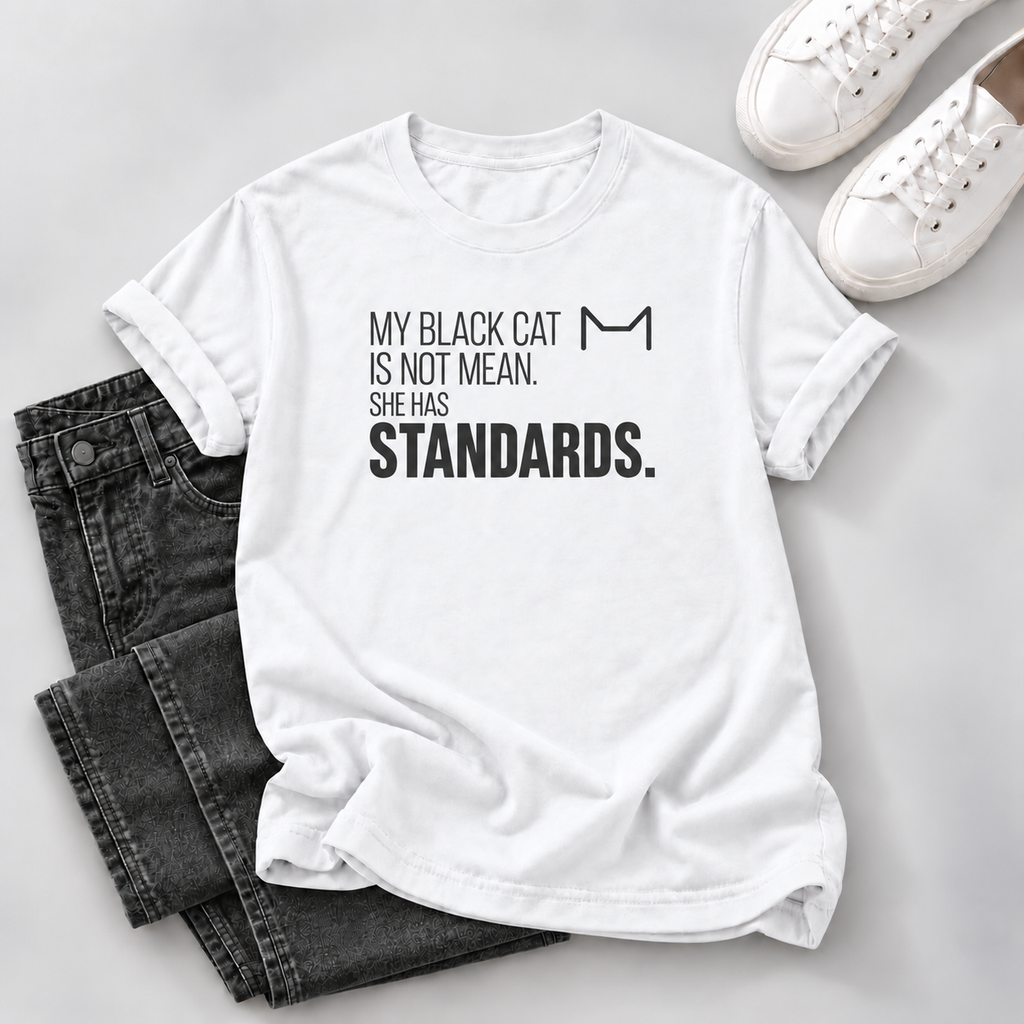 White T-shirt with black “My Black Cat Is Not Mean. She Has Standards.” lettering and a cat-ear outline, styled with dark jeans and white sneakers.