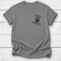 Gray T-shirt with a black paw print between “Stay” and “Pawsitive” on the left chest, with rolled sleeves, laid flat on white wooden board